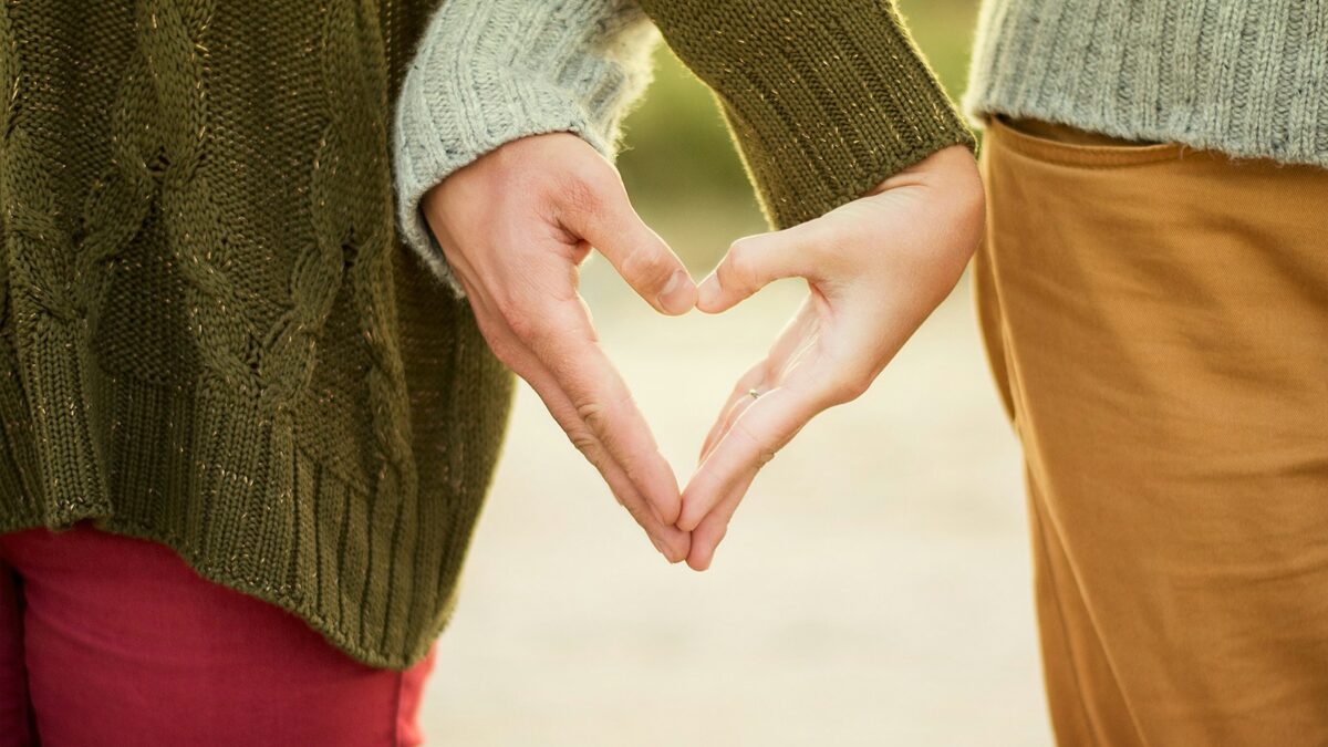 person forming heart shape with their hands