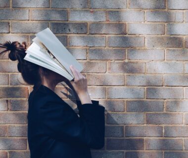 woman covering her face with white book