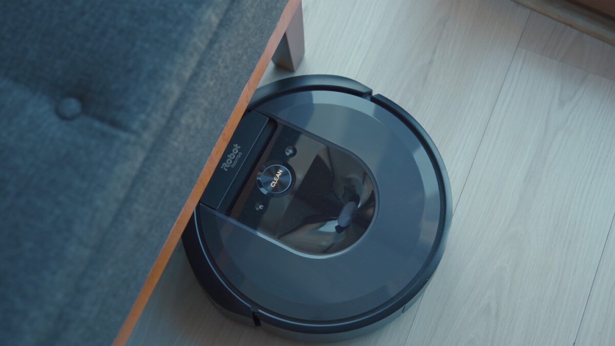 a robotic vacuum is on the floor next to a couch