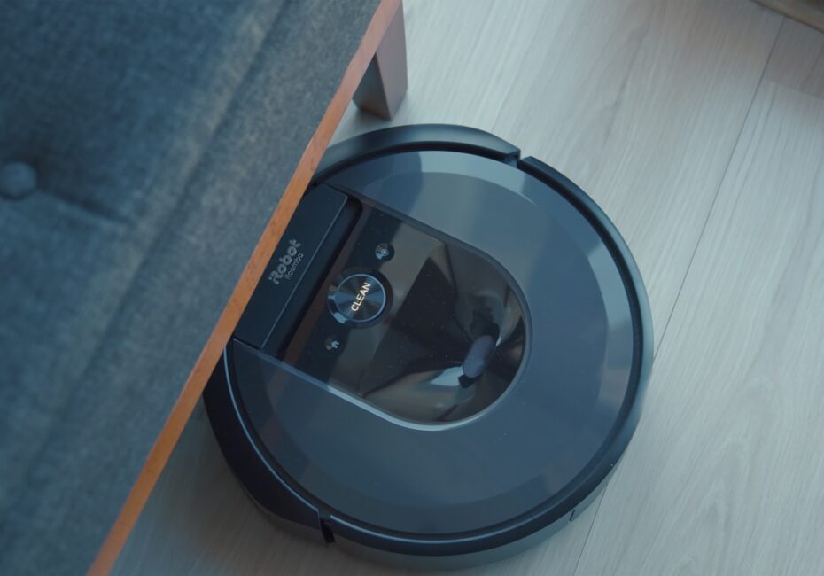 a robotic vacuum is on the floor next to a couch