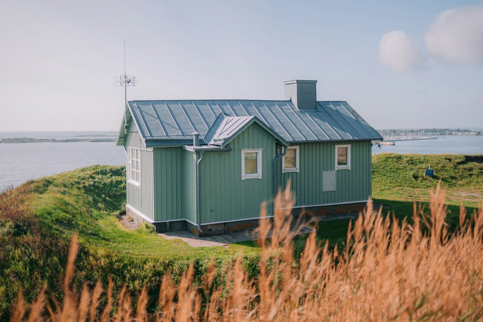 a small green house sitting on top of a lush green hillside